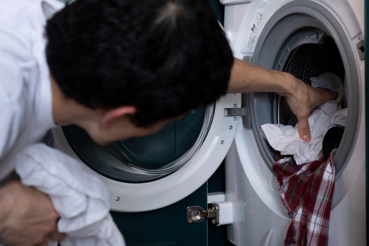 Mastering the First Impression: Your intriguing post title goes here Close-up of a man placing clothes into a washing machine during household chores.